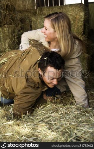Young adult Caucasian couple playing in hay.