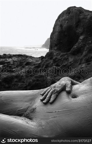 Young adult Caucasian female nude lying on back in Maui, Hawaii.