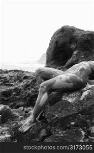 Young adult Caucasian female nude lying on rock in Maui.