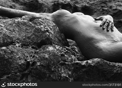 Young adult Caucasian female nude lying on rocky coast of Maui, Hawaii.