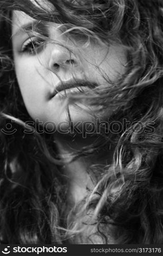 Young adult Caucasian female with hair blowing in face looking at viewer.