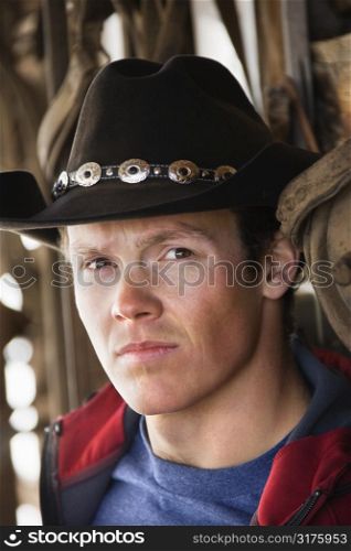 Young adult Caucasian male wearing cowboy hat looking at viewer.