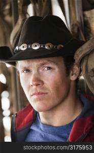 Young adult Caucasian male wearing cowboy hat looking at viewer.
