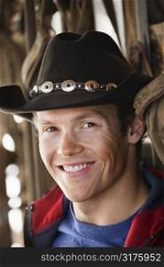 Young adult Caucasian male wearing cowboy hat smiling at viewer.
