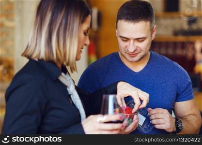 Young adult caucasian man and woman holding glass of wine offering strawberries wearing blue shirt happy side view at home party day