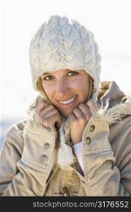 Young adult Caucasian woman in winter attire holding collar and smiling at viewer.