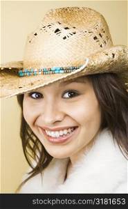 Young adult Caucasian woman wearing cowboy hat smiling at viewer.