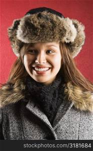 Young adult Caucasian woman wearing fur hat looking to side and smiling.
