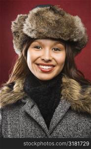 Young adult Caucasian woman wearing fur hat smiling at viewer.
