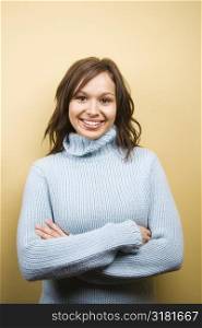 Young adult Caucasian woman wearing sweater with arms crossed and smiling at viewer.