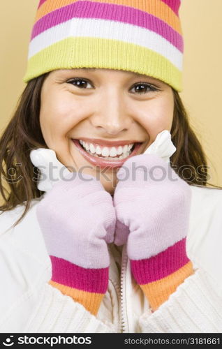 Young adult Caucasian woman wearing winter hat and gloves and smiling at viewer.