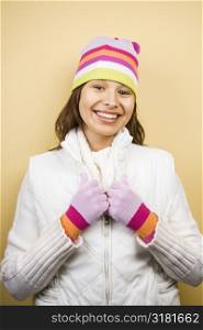Young adult Caucasian woman wearing winter hat and gloves and smiling at viewer.