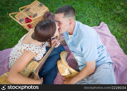 Young Adult Couple with Guitar Kissing in the Park.