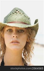Young adult female Caucasian on beach wearing cowboy hat.