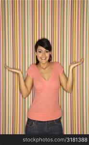 Young adult female Caucasian shrugging on striped background.