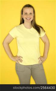 Young adult female Caucasian standing smiling on yellow background.