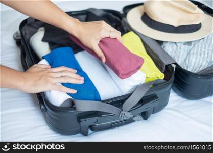 Young adult female packing luggage for summer vacation. woman tourist checking list travel accessories in suitcase on the bed. Time to travel, relaxation, journey, trip and weekend concepts