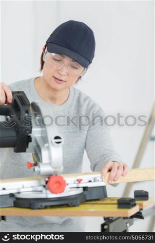 young adult female woodworker cutting board in workshop