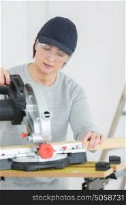 young adult female woodworker cutting board in workshop