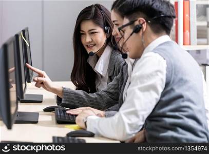 Young adult friendly and confidence operator asian man agent with headsets working in a call center with his colleague team working as customer service and technical support workplace in background.
