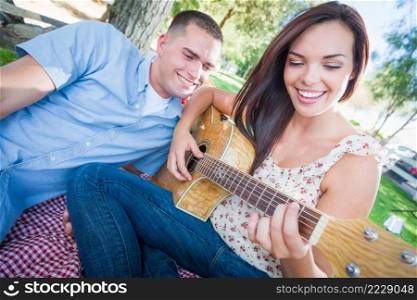 Young Adult Girl Playing Guitar with Boyfriend In The Park.