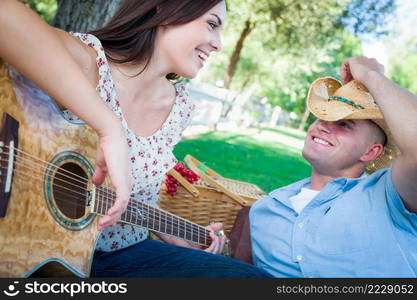 Young Adult Girl Playing Guitar with Boyfriend In The Park.