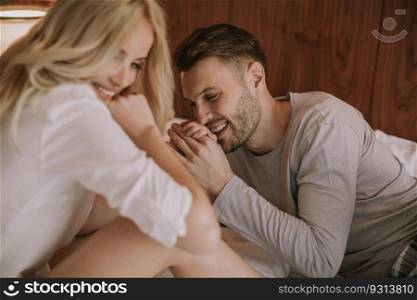 Young adult heterosexual couple on bed in bedroom at home