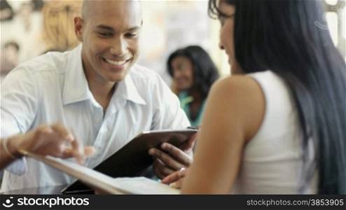 Young adult hispanic couple dining out in restaurant and reading menu. Dolly shot