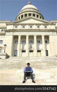 Young adult male working on a laptop computer on the steps of a government building. Shot with a Canon 20D.
