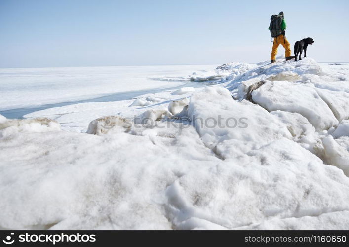 Young adult man outdoors with his dog exploring winter landscape