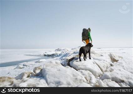 Young adult man outdoors with his dog exploring winter landscape