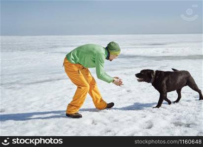 Young adult man outdoors with his dog having fun in winter landscape