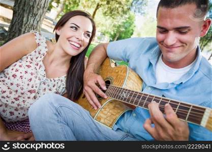 Young Adult Man Playing Guitar for His Girlfriend in the Park.