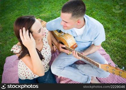 Young Adult Man Playing Guitar for His Girlfriend in the Park.