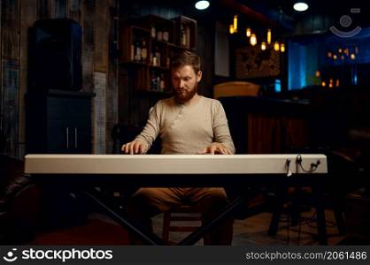 Young adult man playing synthesizer at home apartment. Guy musician composing music. Young adult man playing synthesizer at home