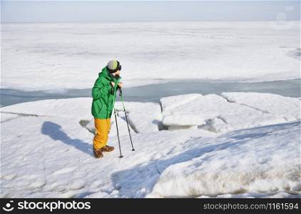 Young adult man with walking sticks outdoors exploring icy landscape