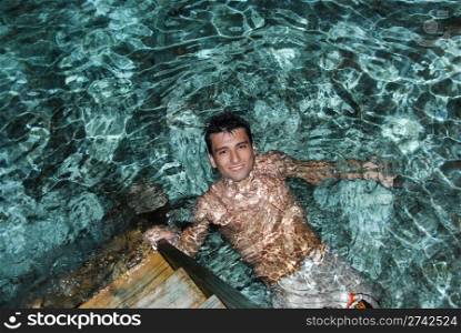 young adult smiling on translucid water in a Maldivian Island (night shoot)