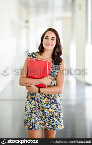 Young adult student woman in a hallway of her school smiling. Lifestyle and university education concepts.. Young adult student woman in a hallway of her school.