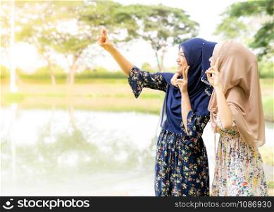 Young adult teenager Muslim Islamic Thai Asian women university students using smartphones to make thier selfie photographing