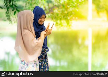 Young adult teenager Muslim Islamic Thai Asian women using smartphones and tablet in social media.