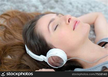 young adult woman lying on the floor listening to music
