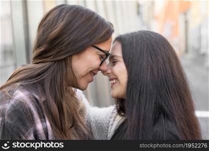 Young affectionate lesbian couple standing outdoors in city. High quality photo.. Young affectionate lesbian couple standing outdoors in city