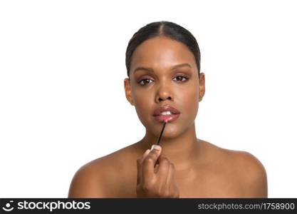 Young African-American beauty model with flawless and smooth skin seriously applying lipstick on a white background.