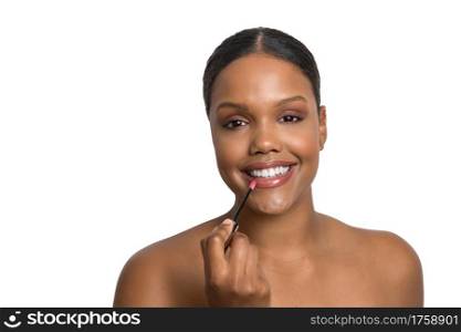 Young African American beauty model with flawless and smooth skin smiling applying lipstick on a white background