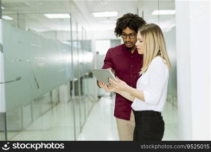 Young African american businessman and caucasian businesswoman with tablet pc computer standing in office