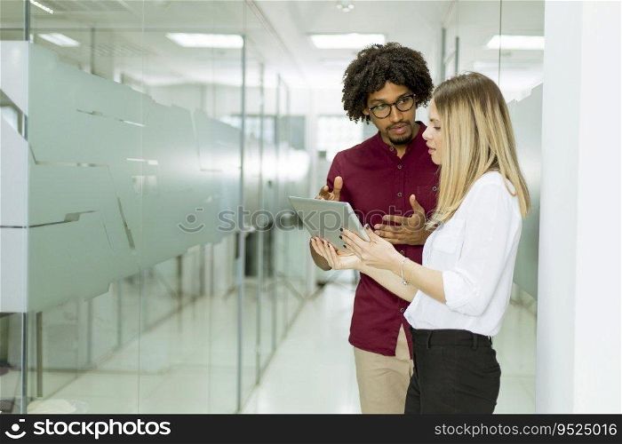 Young African american businessman and caucasian businesswoman with tablet pc computer standing in office