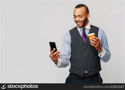 Young African-american Businessman holding Phone And Coffee to go over light grey background.. Young African-american Businessman holding Phone And Coffee to go over light grey background