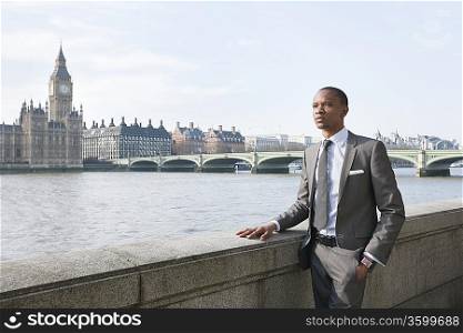 Young African American businessman looking away with hand in pocket
