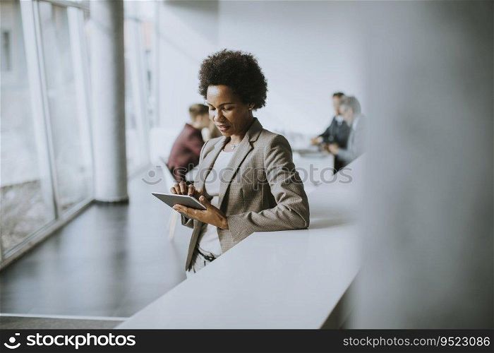 Young African American businesswoman standing and using digital tablet in the modern office