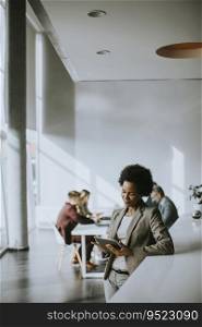 Young African American businesswoman standing and using digital tablet in the modern office